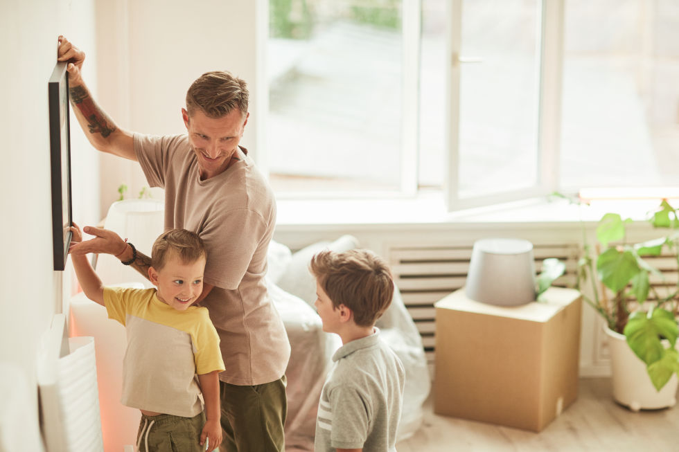 Padre e hijos decoran la sala de estar de una vivienda.